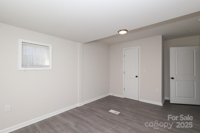 empty room with visible vents, baseboards, and dark wood-type flooring