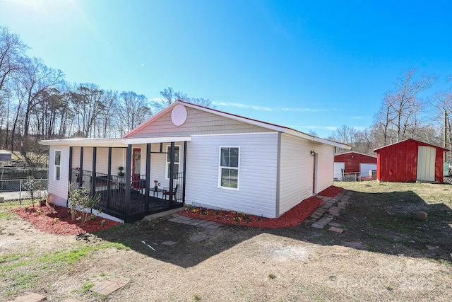 view of front of house featuring covered porch, a storage unit, and an outbuilding