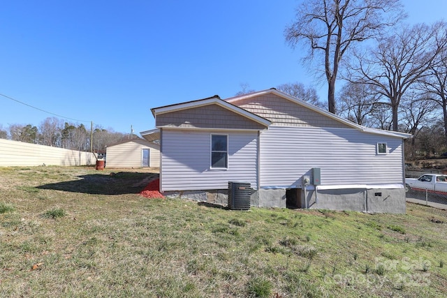 view of side of home featuring a yard, fence, and central AC unit