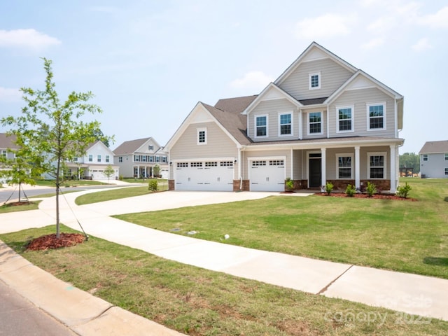 craftsman inspired home with a garage, a front yard, concrete driveway, and covered porch