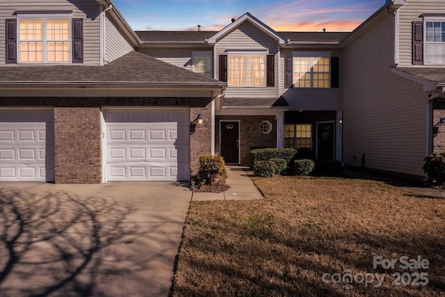 townhome / multi-family property featuring an attached garage, driveway, brick siding, and a shingled roof