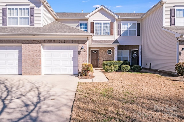 multi unit property featuring a garage, brick siding, driveway, and a shingled roof