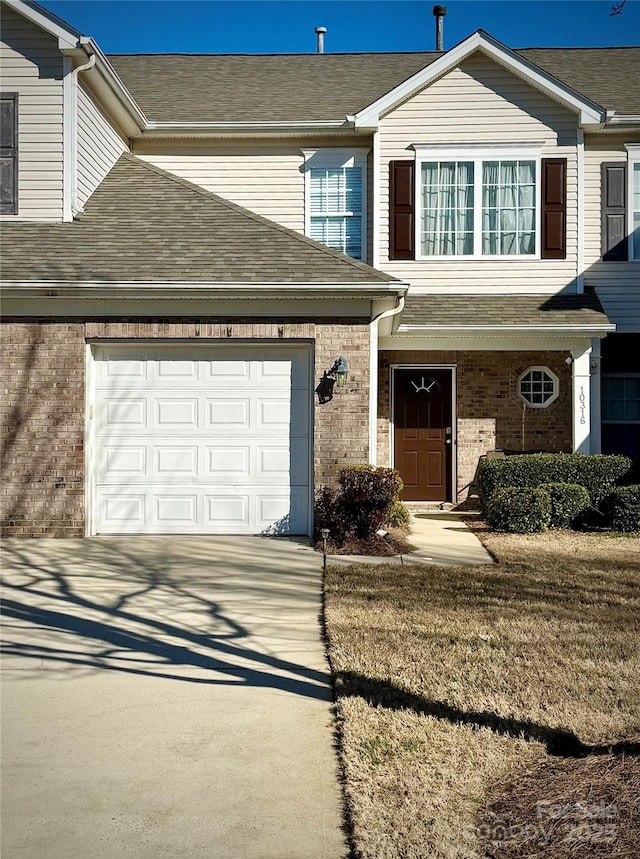 multi unit property featuring an attached garage, driveway, brick siding, and a shingled roof