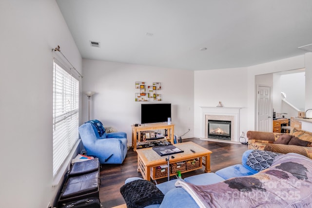 living area with dark wood-style floors, visible vents, and a fireplace