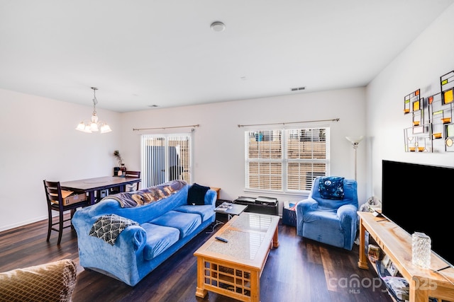 living area featuring dark wood-style floors, visible vents, plenty of natural light, and an inviting chandelier