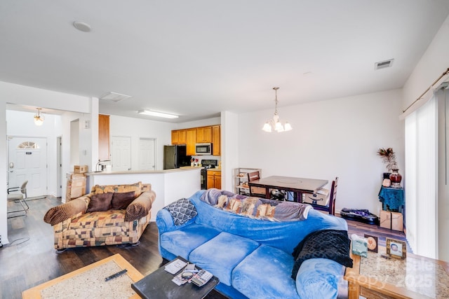 living area featuring dark wood-type flooring, visible vents, and a notable chandelier