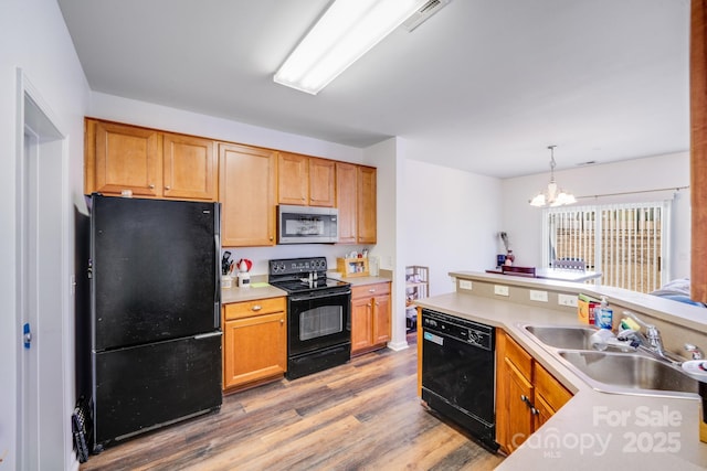 kitchen featuring black appliances, light countertops, a sink, and wood finished floors