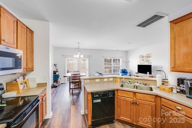 kitchen featuring a sink, visible vents, hanging light fixtures, light countertops, and black appliances