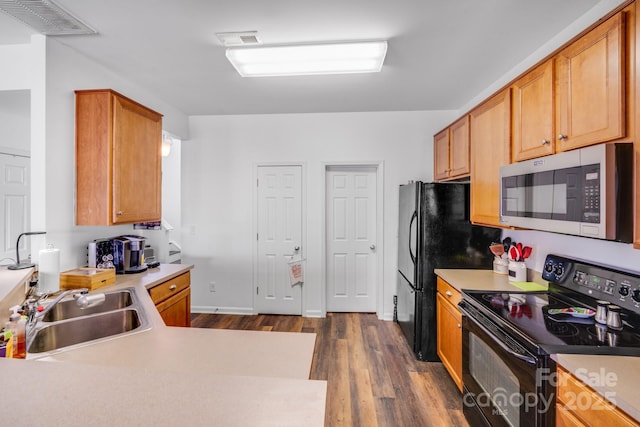 kitchen featuring dark wood-type flooring, a sink, visible vents, light countertops, and black appliances