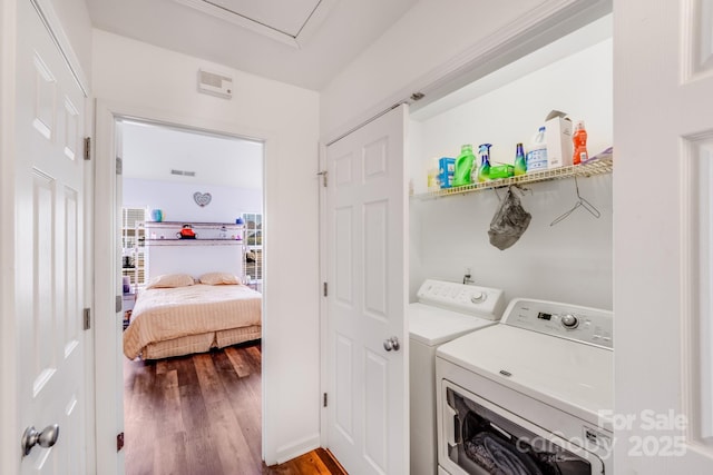 clothes washing area with laundry area, washing machine and clothes dryer, and wood finished floors