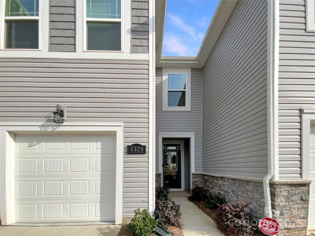 property entrance with a garage and stone siding