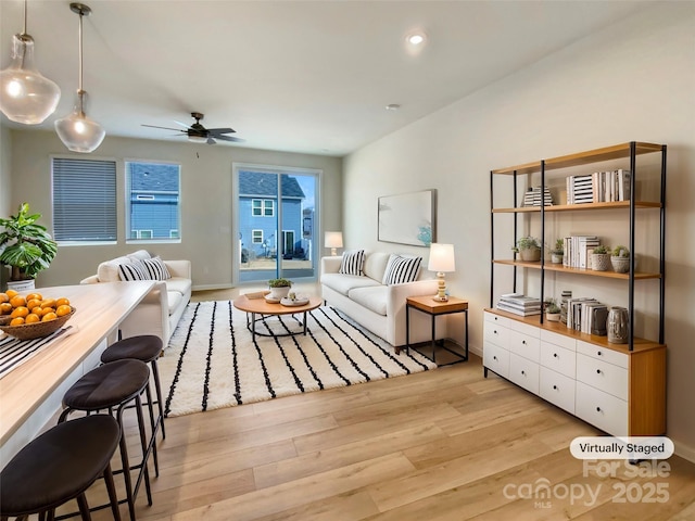 living area featuring baseboards, light wood finished floors, a ceiling fan, and recessed lighting