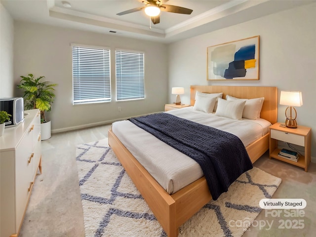 bedroom featuring light carpet, ceiling fan, and a tray ceiling