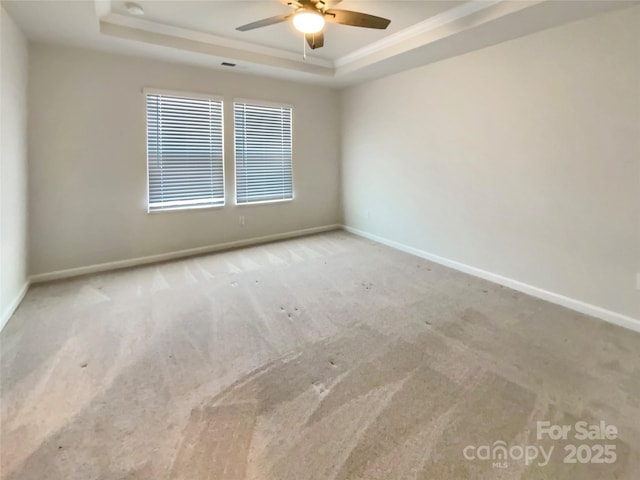 carpeted spare room with a tray ceiling and ceiling fan