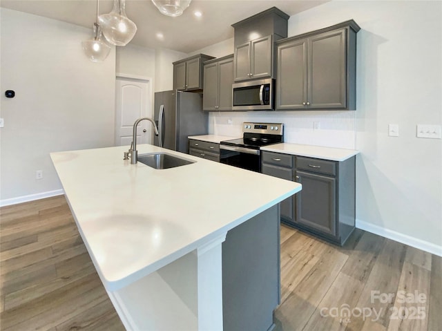 kitchen featuring gray cabinets, sink, stainless steel appliances, and an island with sink