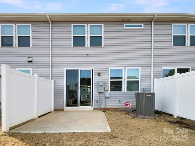 back of property with central AC unit and a patio