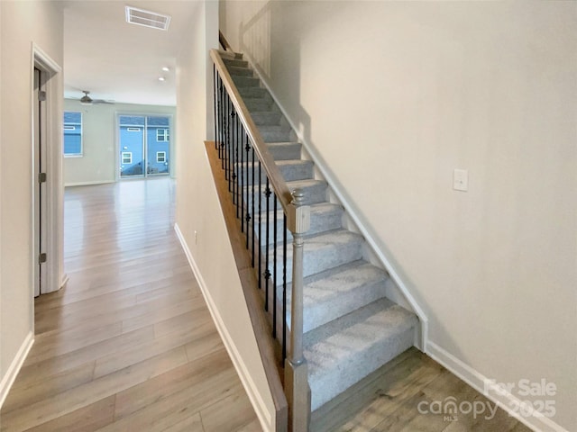 stairway featuring ceiling fan and wood-type flooring