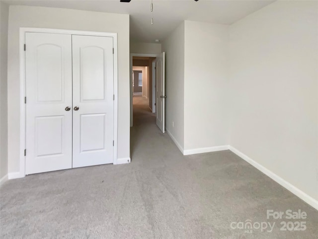 unfurnished bedroom with a closet and light colored carpet