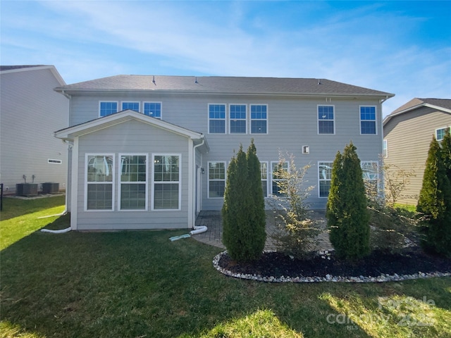 rear view of property with central AC and a yard