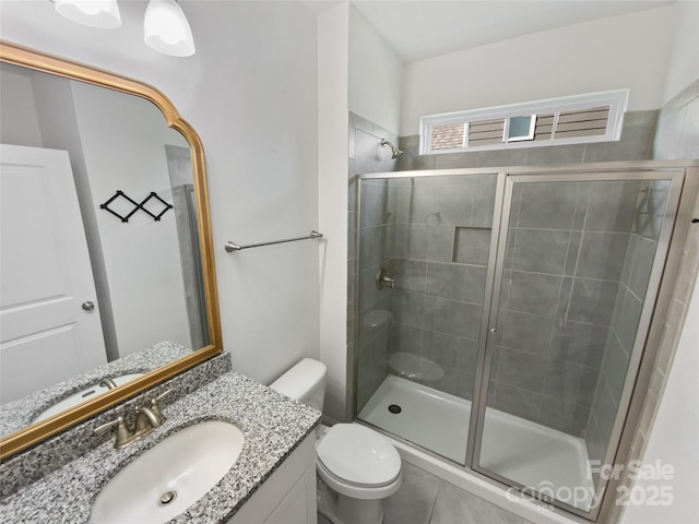 bathroom with toilet, vanity, and a shower with shower door