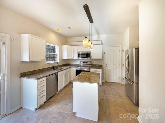 kitchen with stainless steel appliances, decorative light fixtures, a kitchen island, sink, and white cabinets