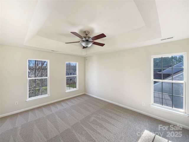 unfurnished room with a tray ceiling, ceiling fan, and light carpet