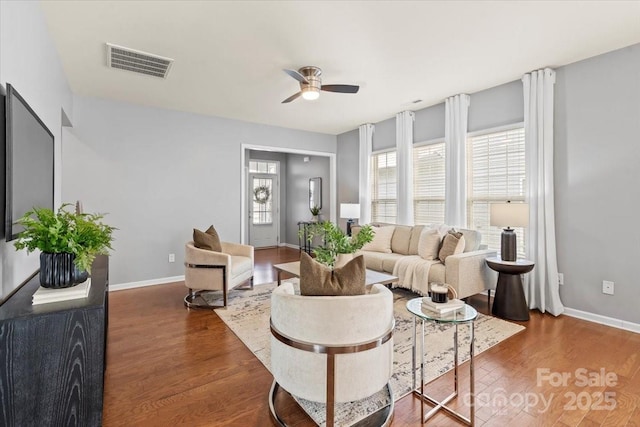 living room with wood finished floors, visible vents, ceiling fan, and a healthy amount of sunlight