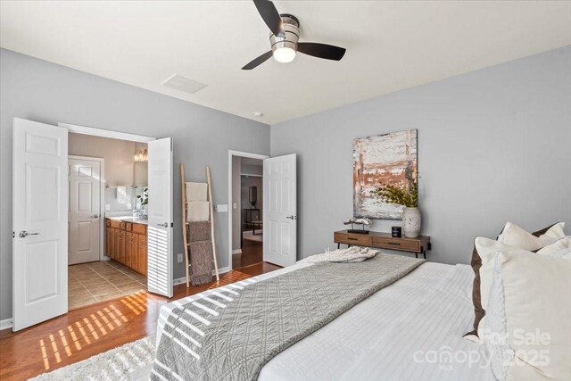 bedroom with light wood-type flooring, visible vents, connected bathroom, and ceiling fan