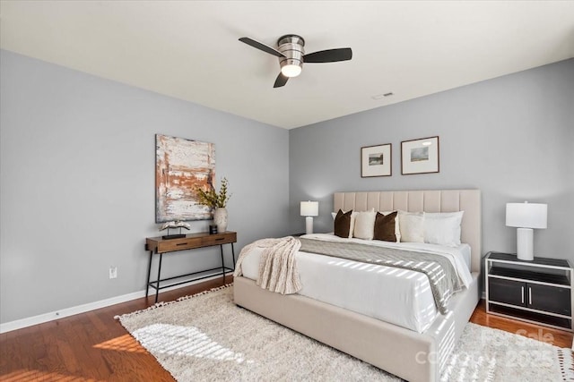 bedroom with baseboards, a ceiling fan, wood finished floors, and visible vents