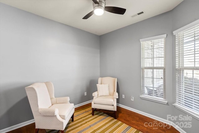 living area with ceiling fan, baseboards, a healthy amount of sunlight, and visible vents