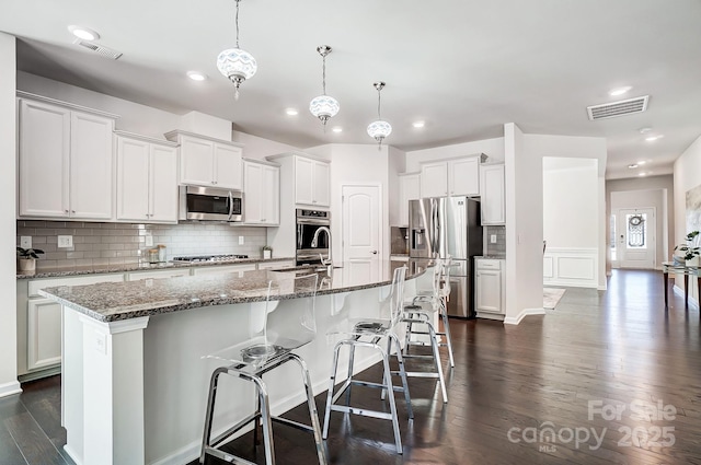 kitchen with white cabinets, a kitchen island with sink, visible vents, and stainless steel appliances