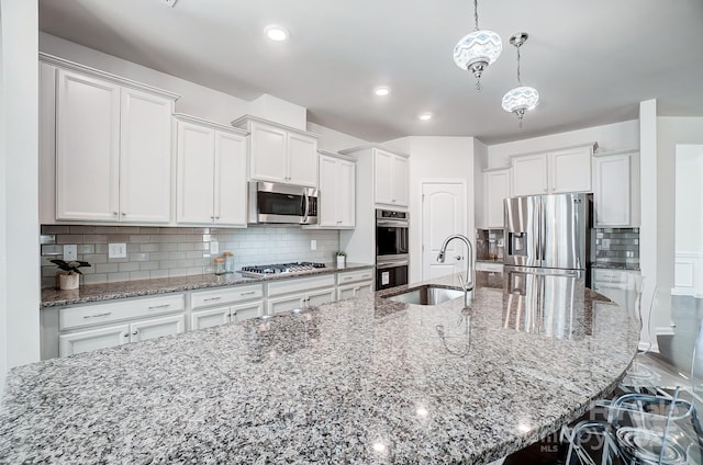 kitchen featuring a large island, appliances with stainless steel finishes, a breakfast bar, decorative light fixtures, and a sink