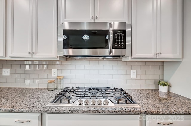 kitchen featuring appliances with stainless steel finishes, decorative backsplash, white cabinetry, and light stone countertops