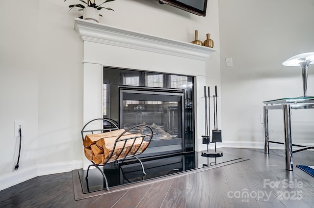 interior details with baseboards, wood finished floors, and a glass covered fireplace