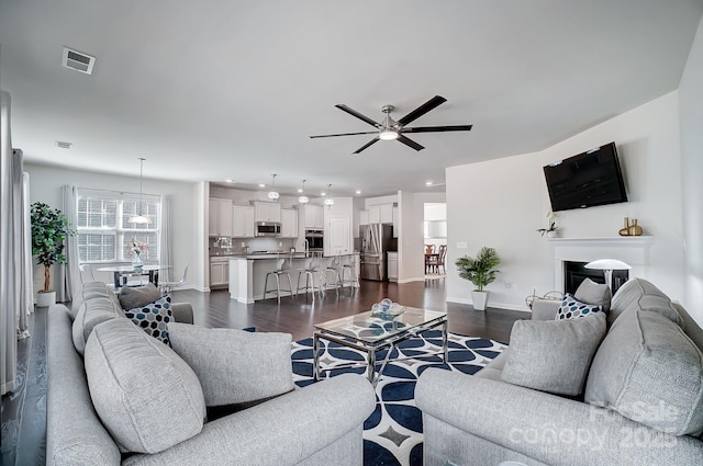 living area featuring ceiling fan, recessed lighting, dark wood-type flooring, visible vents, and baseboards