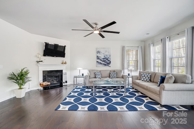 living room with baseboards, a fireplace with flush hearth, a ceiling fan, and wood finished floors