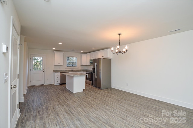 kitchen featuring a sink, visible vents, baseboards, appliances with stainless steel finishes, and a center island