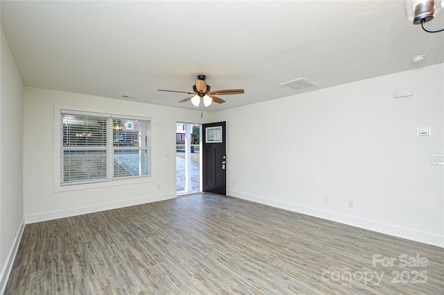 empty room with a ceiling fan, visible vents, baseboards, and wood finished floors