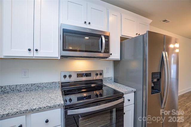 kitchen featuring appliances with stainless steel finishes, white cabinets, visible vents, and light stone countertops