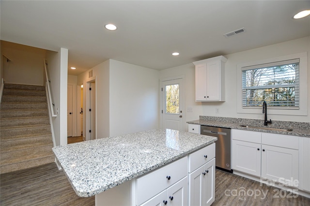 kitchen with white cabinets, dark wood-type flooring, stainless steel dishwasher, a sink, and recessed lighting