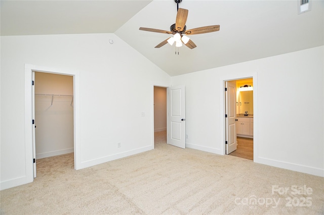 unfurnished bedroom featuring a walk in closet, lofted ceiling, visible vents, carpet flooring, and baseboards