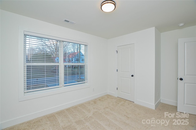 empty room featuring carpet, visible vents, and baseboards