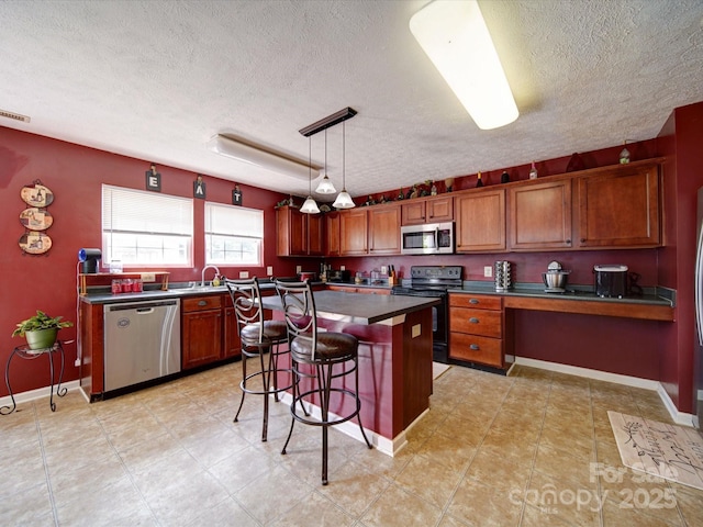 3841 Shasta Cir, Clover, SC 29710 - kitchen featuring stainless steel appliances, brown cabinetry, a textured ceiling, a breakfast bar area, and a center island