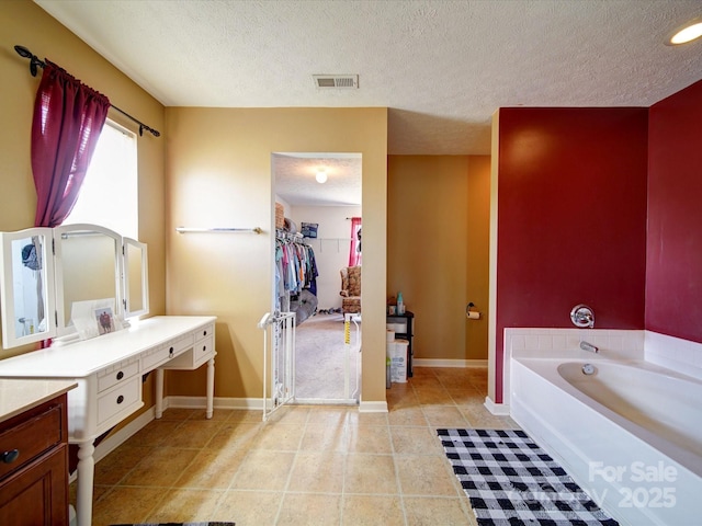 3841 Shasta Cir, Clover, SC 29710 - bathroom featuring a textured ceiling, baseboards, a bath, vanity, and a walk in closet