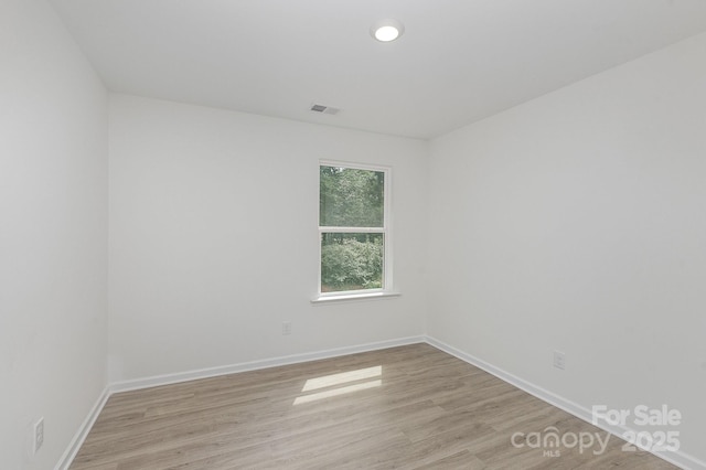 spare room with light wood-style floors, visible vents, and baseboards