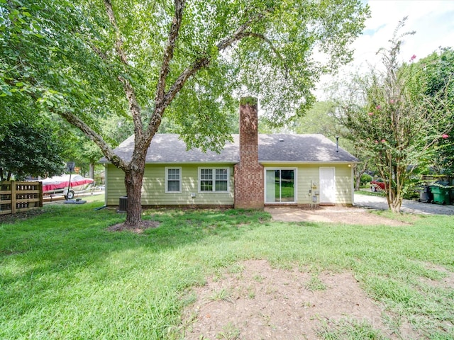 back of house featuring a patio area, a chimney, central AC unit, and a lawn