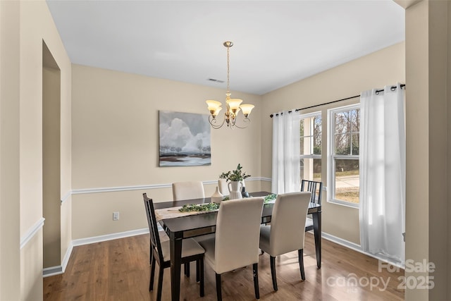 dining room with a chandelier, visible vents, baseboards, and wood finished floors