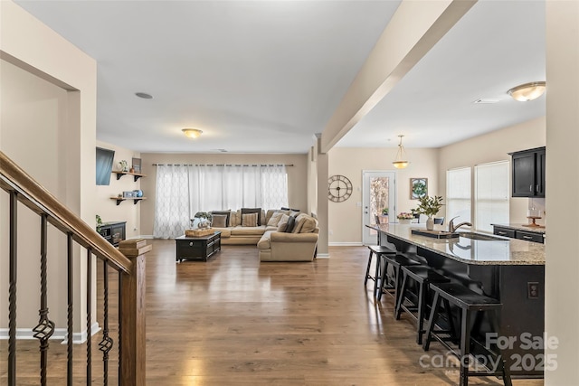 living room featuring a glass covered fireplace, dark wood-style flooring, stairway, and baseboards