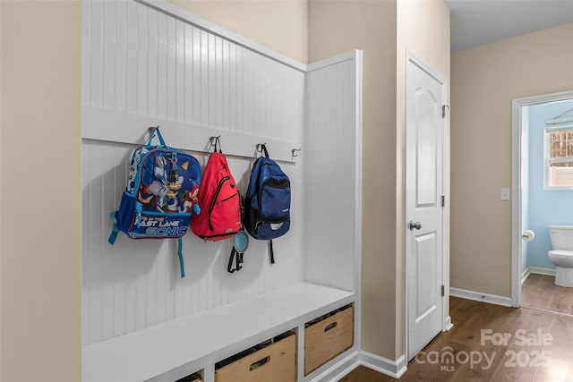 mudroom with dark wood finished floors and baseboards