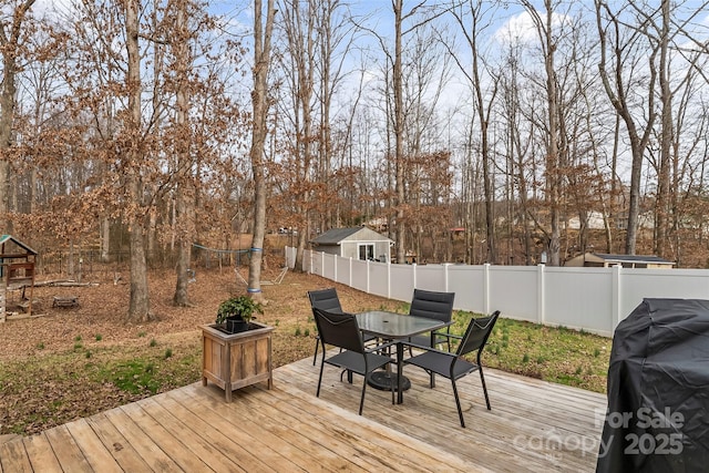 wooden deck with outdoor dining area, grilling area, and a fenced backyard